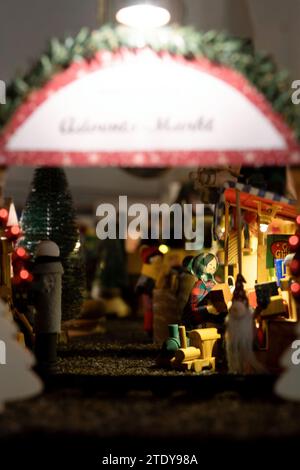 Coburg, Deutschland. Dezember 2023. Eine Miniatur-Dame kauft Spielzeug auf einem Weihnachtsmarkt. Rund 20 Meter vom Coburger Marktplatz entfernt, hat der ausgebildete Sozialarbeiter und jetzt Rentner Horst Gründel eine einzigartige, detailreiche Winterwelt geschaffen. In einem Raum in seiner Wohnung befindet sich ein kleiner Weihnachtsmarkt mit einer Größe von etwa acht Quadratmetern. Über 30 Stände, eine Modelleisenbahn, vier Krippen, eine Gondel, ein Karussell und vieles mehr beleben die Landschaft. Gründel begann in den 1970er Jahren mit dem Bau der ersten Verkaufsstände Quelle: Pia Bayer/dpa/Alamy Live News Stockfoto