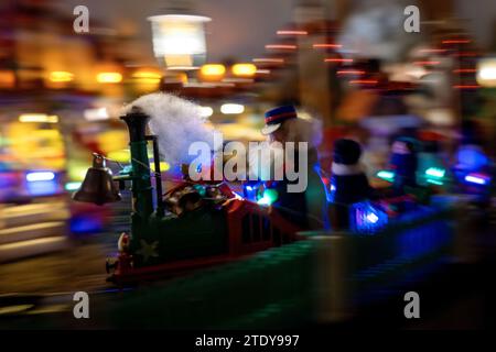 PRODUKTION - 05. Dezember 2023, Bayern, Coburg: Eine berauschende Weihnachtswelt: Eine Modellbahn fährt an den Ständen eines Miniatur-Weihnachtsmarktes vorbei. Rund 20 Meter vom Coburger Marktplatz entfernt, hat der ausgebildete Sozialarbeiter und jetzt Rentner Horst Gründel eine einzigartige, detailreiche Winterwelt geschaffen. In einem Raum in seiner Wohnung befindet sich ein kleiner Weihnachtsmarkt mit einer Größe von etwa acht Quadratmetern. Über 30 Stände, eine Modelleisenbahn, vier Krippen, eine Gondel, ein Karussell und vieles mehr beleben die Landschaft. Gründel begann in den 1970er Jahren mit dem Bau der ersten Verkaufsstände Foto: Pia B Stockfoto