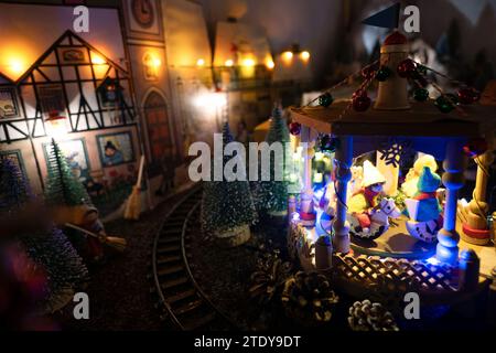 Coburg, Deutschland. Dezember 2023. Ein Karussell macht seine Runden mitten auf einem kleinen Weihnachtsmarkt. Rund 20 Meter vom Coburger Marktplatz entfernt, hat der ausgebildete Sozialarbeiter und jetzt Rentner Horst Gründel ein einzigartiges, detailreiches Winterwunderland geschaffen. In einem Raum in seiner Wohnung befindet sich ein kleiner Weihnachtsmarkt mit einer Größe von etwa acht Quadratmetern. Über 30 Stände, eine Modelleisenbahn, vier Krippen, eine Gondel, ein Karussell und vieles mehr beleben die Landschaft. Gründel begann in den 1970er Jahren mit dem Bau der ersten Verkaufsstände Quelle: Pia Bayer/dpa/Alamy Live News Stockfoto