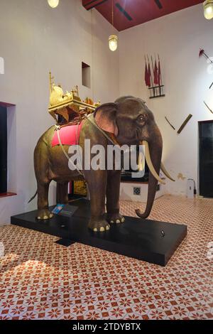 Eine Ausstellung eines lebensgroßen Modells eines Elefanten mit königlicher Halterung, Stuhl, Träger aus goldbedecktem geschnitztem Holz. Im Nationalmuseum in Bangkok, Stockfoto