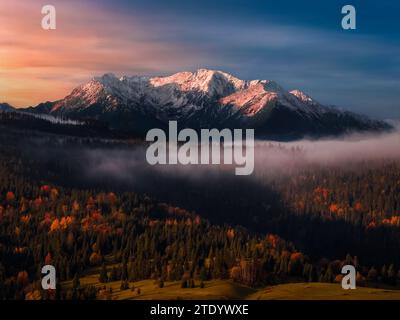 Slowakei - Herbstblick aus der Vogelperspektive auf die Gipfel der Hohen Tatra im Nationalpark bei Sonnenaufgang mit farbenfrohem Herbstlaub, Nebel und dramatischem Gol Stockfoto