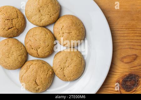 Ingwerkekse isoliert auf weißer Platte - Ingwerknöpfe auf Platte mit Holztisch Kopierraum Stockfoto