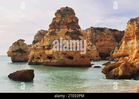 Große Felsen im Wasser an einem Sandstrand im Süden Portugals an einem Wintertag. Stockfoto