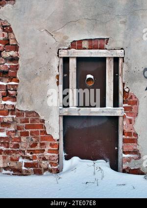 Beschädigter Putz an roter Ziegelwand im Winter Stockfoto