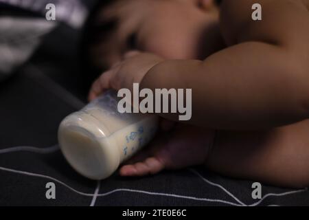 Baby mit Flasche im bequemen Bett. Das Baby Trinkt Milch Aus Der Flasche. Stockfoto