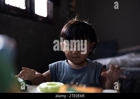 Kleinkinder spielen zu Hause mit einem Holzspielzeug. Kleinkinder spielen mit einem farbigen Lernspielzeug. Kinderspiel am Tisch im Babyzimmer. Kindliche Entwicklung. Stockfoto