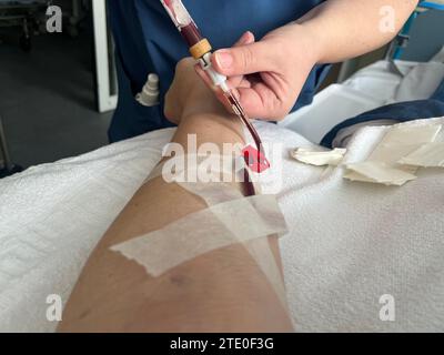 Eine Krankenschwester zieht Blut aus einer Vene im Unterarm eines Mannes. Stockfoto