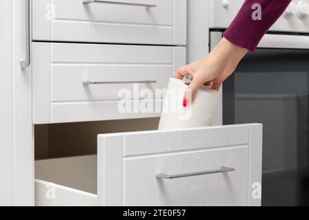 Frau, die Papierhandtuch aus der Küchenschublade herausnimmt. Die Hand nimmt ein Papiertuch heraus. Stockfoto