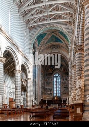 Orvieto, Italien - 18. November 2023: Innenansicht des zentralen Kirchenschiffs der Kathedrale von Orvieto mit Bänken und vielen Statuen Stockfoto