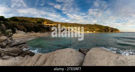 Panoramablick auf den Strand Cavoli auf Elba im warmen Abendlicht und Felsbrocken im Vordergrund Stockfoto