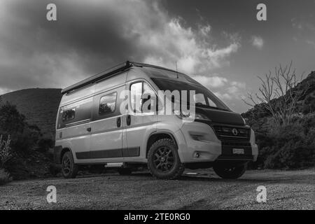 Ein Schwarzweiß-Blick auf einen Wohnmobil, der auf einer unbefestigten Straße geparkt ist Stockfoto