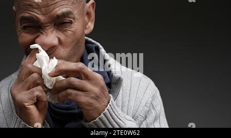 Mann, der die Erkältung und Grippe fängt Mann, der Nase bläst, nachdem er eine Erkältung mit grauem Hintergrund mit Leuten Stock Foto gefangen hat Stockfoto