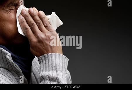Mann, der die Erkältung und Grippe fängt Mann, der Nase bläst, nachdem er eine Erkältung mit grauem Hintergrund mit Leuten Stock Foto gefangen hat Stockfoto