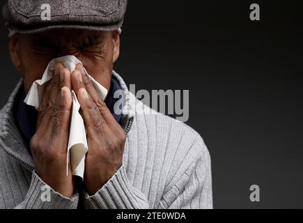 Mann, der die Erkältung und Grippe fängt Mann, der Nase bläst, nachdem er eine Erkältung mit grauem Hintergrund mit Leuten Stock Foto gefangen hat Stockfoto