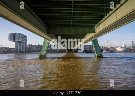 Unter der Severiner Brücke über den Rhein bei Flut, links eines der Kranhäuser im Rheinauhafen, rechts das Schokoladenmuseum, Stockfoto