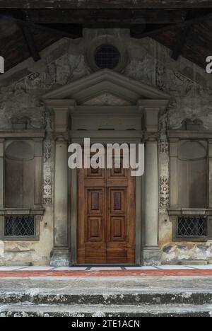 Westeingang zur mittelalterlichen Chiesa di Santa Maria Primerana, auf der Piazza Mino da Fiesole in Fiesole, einer Stadt oberhalb von Florenz, Toskana, Italien. Der Eingang befindet sich unter einem ionischen Portikus, der der Kirche 1801 hinzugefügt wurde. Eine neue Fassade mit Sgraffito-Verzierungen wurde Ende der 1500er Jahre der Kirche hinzugefügt Stockfoto