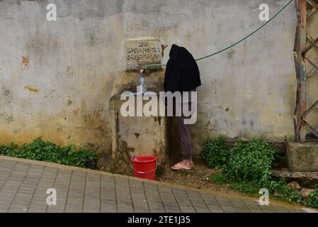 Eine einheimische Frau, die Wasser aus einem öffentlichen Wasserhahn auf El Amir Fakhreddine vor der Zitadelle von Tripolis im Libanon bekommt. "Bob" meinte wahrscheinlich "bring deinen eigenen Eimer mit"? Stockfoto