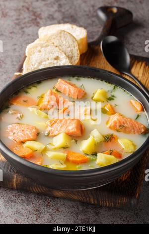 Finnische Wildlachssuppe mit Sahne und Wurzelgemüse in Nahaufnahme auf einem Teller auf dem Tisch. Vertikal Stockfoto