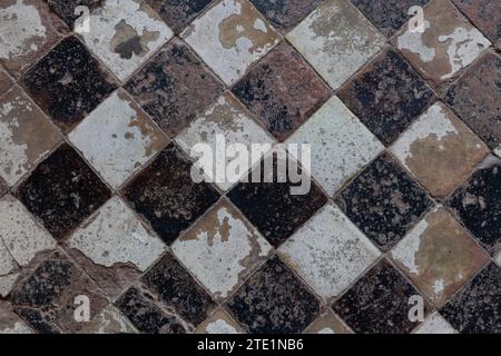 High-angle view of a mosaic of a vintage, diamond pattern layout of black and white floor tiles. Stockfoto