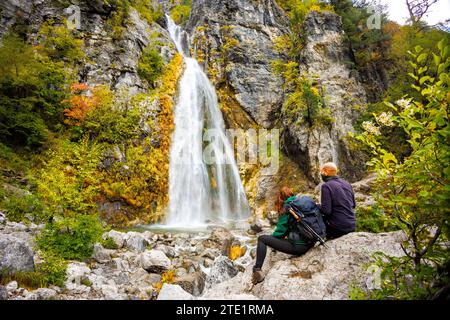 Menschen, die vor dem Wasserfall in Theth, Albanien, sitzen Stockfoto