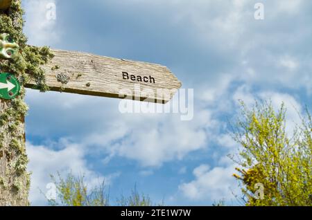 Verwitterter, hölzerner Wegweiser zum Strand, bedeckt mit Flechten, der in Richtung A Beach, Ham Common, Poole, Großbritannien zeigt Stockfoto