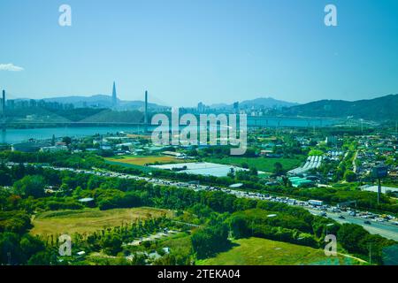 Guri City, Südkorea - 30. September 2023: Ein weitläufiger Blick vom Guri Tower aus fängt das grüne Grün und die Straßen von Guri City mit dem Godeok Gran ein Stockfoto