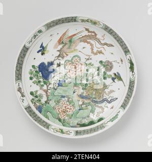 Untertasse mit Felsen, Blumen und Feng Huangs, anonym, ca. 1700 - ca. 1724 Schüssel mit runder, ausbreitender Porzellanwand, in unterschwelliger Glasur blau bemalt und über der Glasur blau, rot, grün, gelb, Aubergine und schwarz. Auf den flachen Felsen mit blühenden Birnzweigen und zwei Feng Huangs, anderen Vögeln und Insekten; der Rand mit geometrischem Muster durchsetzt mit Glückssymbolen (Castagnets, Zepter, Buchrollen, Musikstein, artemisia-Magazin) in Kartuschen. Der Boden mit drei Blütenzweigen. Mit einer Siegelmarke in einem Doppelkreis gekennzeichnet. Vier Chips in der Kante. Famle Verte. Porzellan. G Stockfoto