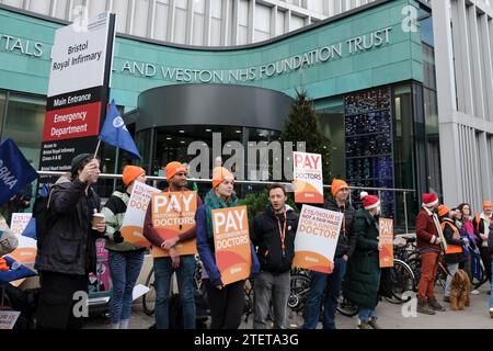 Bristol, Großbritannien. Dezember 2023. Juniorärzte streiken in ihrem laufenden Lohnstreit weiter. Unterstützt von der BMA soll ihr Gehaltsanspruch die Einkommensverluste nach Jahren mit Lohnsteigerungen unter der Inflation wieder herstellen. Viele Ärzte erwägen, den NHS zu verlassen; die Lohnwiederherstellung soll qualifizierte Ärzte halten und den NHS schützen. Diese Runde des Streiks wird von heute an drei Tage dauern und am 3. Januar sechs Tage lang wieder beginnen, was dies zum längsten Streik in der Geschichte des NHS macht. Ärzte sind vor dem Bristol Royal Infirmary oder BRI in Bristol abgebildet. Quelle: JMF News/Alamy Live News Stockfoto