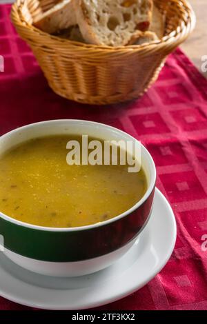 Cremige Gemüsesuppe, serviert in einem Restaurant auf einer leuchtend roten Tischdecke. Stockfoto