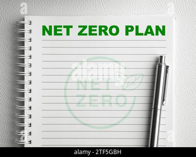 Grüner Text „Net Zero Plan“ oben auf der leeren vertikalen Notizblock-Seite mit silbernem Stift auf weißem Spiralnotizbuch. Klimaneutrale langfristige Strategie Sust Stockfoto