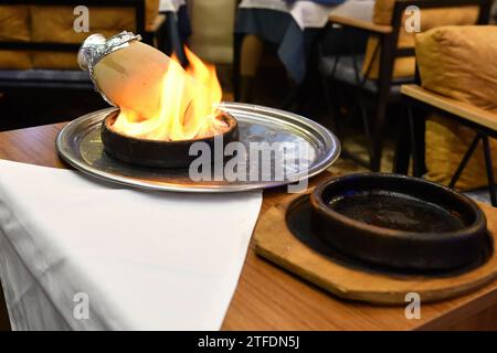 Traditioneller türkischer Testi Kebab, der in Tontopf über Feuer auf dem Tisch gekocht wird Stockfoto