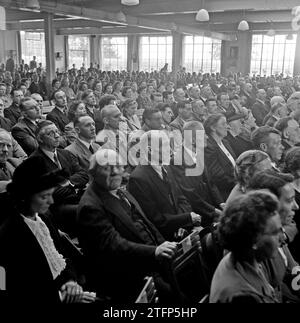 Übersicht über einen Raum mit Sitzpersonen auf Klappstühlen ca. 1950 Stockfoto