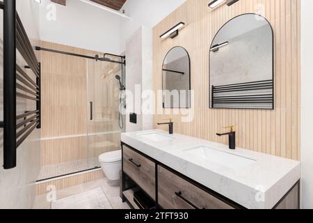 Ein Badezimmer mit einer Wand mit Holzleiste, einer Marmorplatte auf einem schwarzen Holzschrank und einer Dusche mit gefliesten Holzleisten. Keine Marken oder l Stockfoto