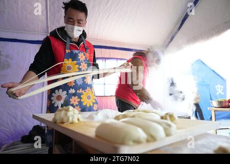 (231220) -- LINXIA, 20. Dezember 2023 (Xinhua) -- Mitarbeiter des Unternehmens bereiten kostenlose Rindfleischnudeln an einer vorübergehenden Umzugsstelle im Dorf Dahe im Jishishan County, nordwestchinesische Provinz Gansu, am 20. Dezember 2023 zu. Laut einer Pressekonferenz am Mittwoch laufen umfassende Rettungs- und Hilfsarbeiten inmitten bitterer Kälte, da ein Erdbeben der Stärke 6,2 113 Menschen getötet und 782 weitere verletzt hat. Insgesamt wurden 87.076 Menschen aus 20.457 Haushalten vorübergehend an sichere Orte verlegt. Notentlastungsmaterialien wie Zelte, Steppdecken, Faltbare Be Stockfoto