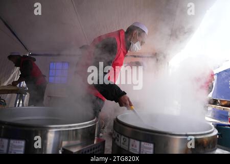 (231220) -- LINXIA, 20. Dezember 2023 (Xinhua) -- Ein Mitarbeiter des Unternehmens bereitet kostenlose Rindfleischnudeln für Menschen an einem vorübergehenden Umzug im Dorf Dahe im Jishishan County, nordwestchinesische Provinz Gansu, 20. Dezember 2023 zu. Laut einer Pressekonferenz am Mittwoch laufen umfassende Rettungs- und Hilfsarbeiten inmitten bitterer Kälte, da ein Erdbeben der Stärke 6,2 113 Menschen getötet und 782 weitere verletzt hat. Insgesamt wurden 87.076 Menschen aus 20.457 Haushalten vorübergehend an sichere Orte verlegt. Nothilfe-Materialien wie Zelte, Steppdecken Stockfoto