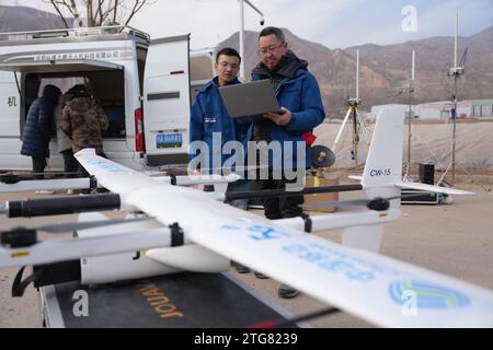 (231220) -- LINXIA, 20. Dezember 2023 (Xinhua) -- He Bo (R), ein Mitarbeiter des China Mobile Chengdu Institute of Research and Development, stellt UAV-Notfallkommunikationsgeräte mit seinem Kollegen an einem vorübergehenden Umzugsort im Dorf Dahe im Jishishishan County, nordwestchinesische Provinz Gansu, am 20. Dezember 2023 ein. Laut einer Pressekonferenz am Mittwoch laufen umfassende Rettungs- und Hilfsarbeiten inmitten bitterer Kälte, da ein Erdbeben der Stärke 6,2 113 Menschen getötet und 782 weitere verletzt hat. Insgesamt waren 87.076 Personen aus 20.457 Haushalten temporär Stockfoto