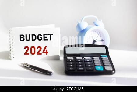 BUDGET 2024 geschrieben auf einem Notizblock und weißem Hintergrund und mit einer Taschenuhr Stockfoto