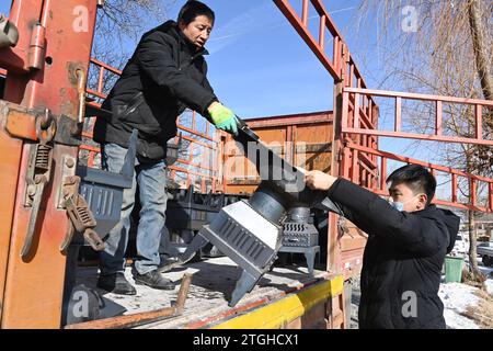 (231220) -- LINXIA, 20. Dezember 2023 (Xinhua) -- Menschen entladen Öfen an einer vorübergehenden Umsiedlungsstelle im Dorf Shenjiaping im Jishishan County, nordwestchinesische Provinz Gansu, 20. Dezember 2023. Laut einer Pressekonferenz am Mittwoch laufen umfassende Rettungs- und Hilfsarbeiten inmitten bitterer Kälte, da ein Erdbeben der Stärke 6,2 113 Menschen getötet und 782 weitere verletzt hat. Insgesamt wurden 87.076 Menschen aus 20.457 Haushalten vorübergehend an sichere Orte verlegt. Notentlastungsmaterialien wie Zelte, Steppdecken, Klappbetten und feuchtigkeitsfeste Matten Stockfoto