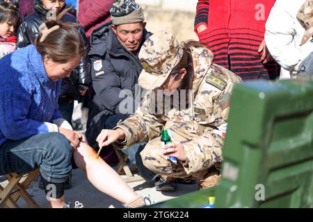 Linxia, Chinas Provinz Gansu. Dezember 2023. Ein Mitglied der People's Armed Police Force (PAPF) bietet medizinische Versorgung für die vom Erdbeben betroffenen Menschen in Liuji Township im Jishishan County, nordwestchinesische Provinz Gansu, 20. Dezember 2023. Die chinesische Volksbefreiungsarmee (PLA) und die Volksarmee (PAPF) haben mehrere Rettungskräfte in Gebieten eingesetzt, die von Erdbeben betroffen sind, als Reaktion auf ein Erdbeben der Stärke 6,2, das die nordwestchinesische Provinz Gansu am späten Montag erschütterte. Quelle: Hou Chonghui/Xinhua/Alamy Live News Stockfoto