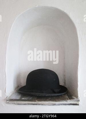 Konzeptkunst, schwarzer Bowler Hut in weißer Nische, wo immer ich meine Mütze lege, ist mein Zuhause. Historisches Image, Tudor-Raum für Waren/Kleidung weg von Nagetieren Stockfoto