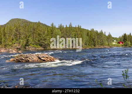 Ein kaskadierender Fluss fließt durch das zerklüftete Gelände von Namsskogan in Trondelag, Norwegen, und bietet einen atemberaubenden Blick auf die ungezähmte natürliche Schönheit Stockfoto