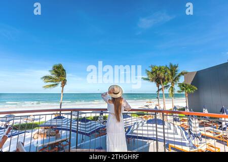 Rückansicht der Frau mit Hut, Blick auf das Meer vom Balkon Stockfoto