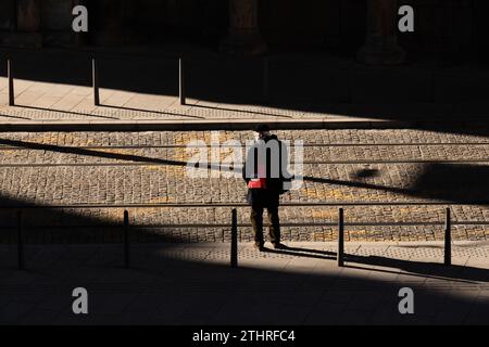 Beograd, Serbien - 19. Dezember 2023: Ein Mann mit weißem Bart steht allein auf einem gepflasterten Bürgersteig mit Straßenbahnschienen, im Sonnenlicht, an Wintertagen mit s Stockfoto