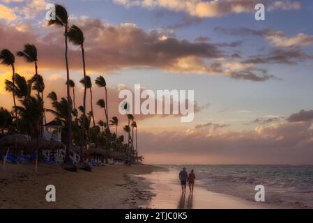 Pärchen, die am Strand bei Sonnenuntergang spazieren gehen. Punta Cana, Dominikanische Republik. Quelle: JDS Stockfoto