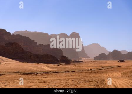 Kamele in der Wüste Wadi Rum, Jordanien. Wadi Rum, auch bekannt als Tal des Mondes, ist ein Tal, das in den Sandstein und Granitfelsen im südlichen Jordanien, nahe der Grenze zu Saudi-Arabien und etwa 60 km (37 mi) östlich der Stadt Aqaba geschnitten wurde. Mit einer Fläche von 720 km2 ist es das größte Wadi (Flusstal) Jordaniens. Mehrere prähistorische Zivilisationen hinterließen Petroglyphen, Felsinschriften und Ruinen in Wadi Rum. Heute ist es eine Touristenattraktion, die geführte Touren, Wandern und Klettern anbietet. Das Naturschutzgebiet Wadi Rum gehört seit 2011 zum UNESCO-Weltkulturerbe. Stockfoto