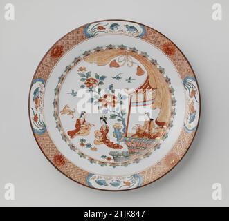 Schüssel mit drei Frauen in der Nähe eines Pavillons, anonym, ca. 1700 - ca. 1724 Porzellanschale, auf der Glasur in Blau, Rot, Grün, Schwarz und Gold gemalt. Auf der Wohnung zwei Teetrinker und ein Hund in einem Garten bei einem Pavillon und Pavillon; Eine dritte Frau ist im Pavillon; der Rand der Wohnung mit einem gebundenen Vorhang; an der Wand ein Reifen mit halbem Blumenhalm; der Rand mit Servierwerk mit Chrysanthemen durchsetzt mit vier gelappten Kartuschen mit Wachtel. In Europa im japanischen Imari-Stil eingerichtet. Chinapainter: Porzellan Europa. Glasur. Gold (Metall) Malerei / Vergoldung / Glasur Porzellan Stockfoto