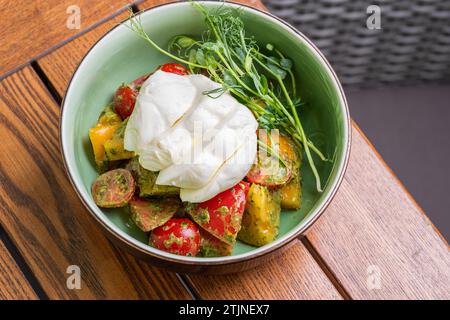 Burrata-Salat mit Kirschtomaten, Pesto und Gewürzen in einer Schüssel. Gesundes Essen, Diät-Mittagessen Konzept. Diätmenü. Essen auf dem Teller. Restaurant-Menü-Konzept. C Stockfoto