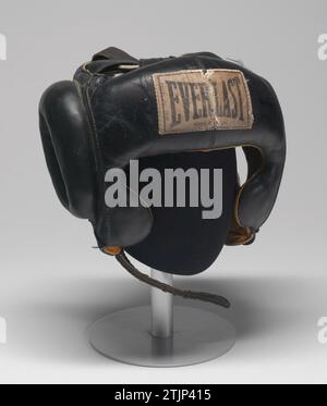 EVERLAST Boxing Maskenbügel im Besitz und getragen von Muhammad Ali Black Boxkopfbügel aus Leder mit gelber Innenausstattung. Offenes Gesicht mit Wangenschutz und verstellbaren Kopf- und Kinnriemen für eine individuelle Passform. „EVERLAST“-Etikett auf der Vorderseite. CA. 1973. Optimierte Version eines Bildes eines Publikationscovers in der National Museum of African Art Collection, National Museum of African Art, Washington DC, USA. Stockfoto