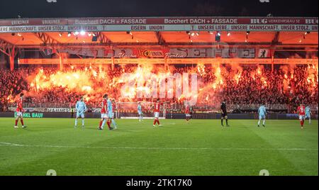 Berlin, Deutschland. Dezember 2023. Fußball: Bundesliga, 1. FC Union Berlin - 1. FC Köln, Spieltag 16, an der Alten Försterei. Gewerkschaftsfans auf der Waldseite zünden ein bengalisches Feuer an. Hinweis: Andreas Gora/dpa – WICHTIGER HINWEIS: gemäß den Vorschriften der DFL Deutscher Fußball-Liga und des DFB Deutscher Fußball-Bundes ist es verboten, im Stadion und/oder des Spiels aufgenommene Fotografien in Form von sequenziellen Bildern und/oder videoähnlichen Fotoserien zu verwenden oder zu nutzen./dpa/Alamy Live News Stockfoto