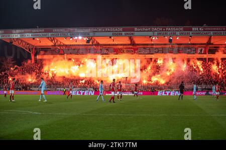 Berlin, Deutschland. Dezember 2023. Fußball: Bundesliga, 1. FC Union Berlin - 1. FC Köln, Spieltag 16, an der Alten Försterei. Gewerkschaftsfans auf der Waldseite zünden ein bengalisches Feuer an. Hinweis: Andreas Gora/dpa – WICHTIGER HINWEIS: gemäß den Vorschriften der DFL Deutscher Fußball-Liga und des DFB Deutscher Fußball-Bundes ist es verboten, im Stadion und/oder des Spiels aufgenommene Fotografien in Form von sequenziellen Bildern und/oder videoähnlichen Fotoserien zu verwenden oder zu nutzen./dpa/Alamy Live News Stockfoto